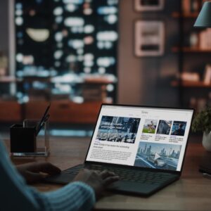 Close Up Shot of a Female Specialist Working on Laptop, Reading Latest News for Market Analysis. Freelancer Female at Home Living Room while Sitting at a Table and Using Computer.